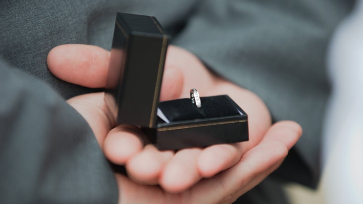Close-up of a groomsman's hands holding the wedding ring at Stewart House and Garden, County Down, Northern Ireland.